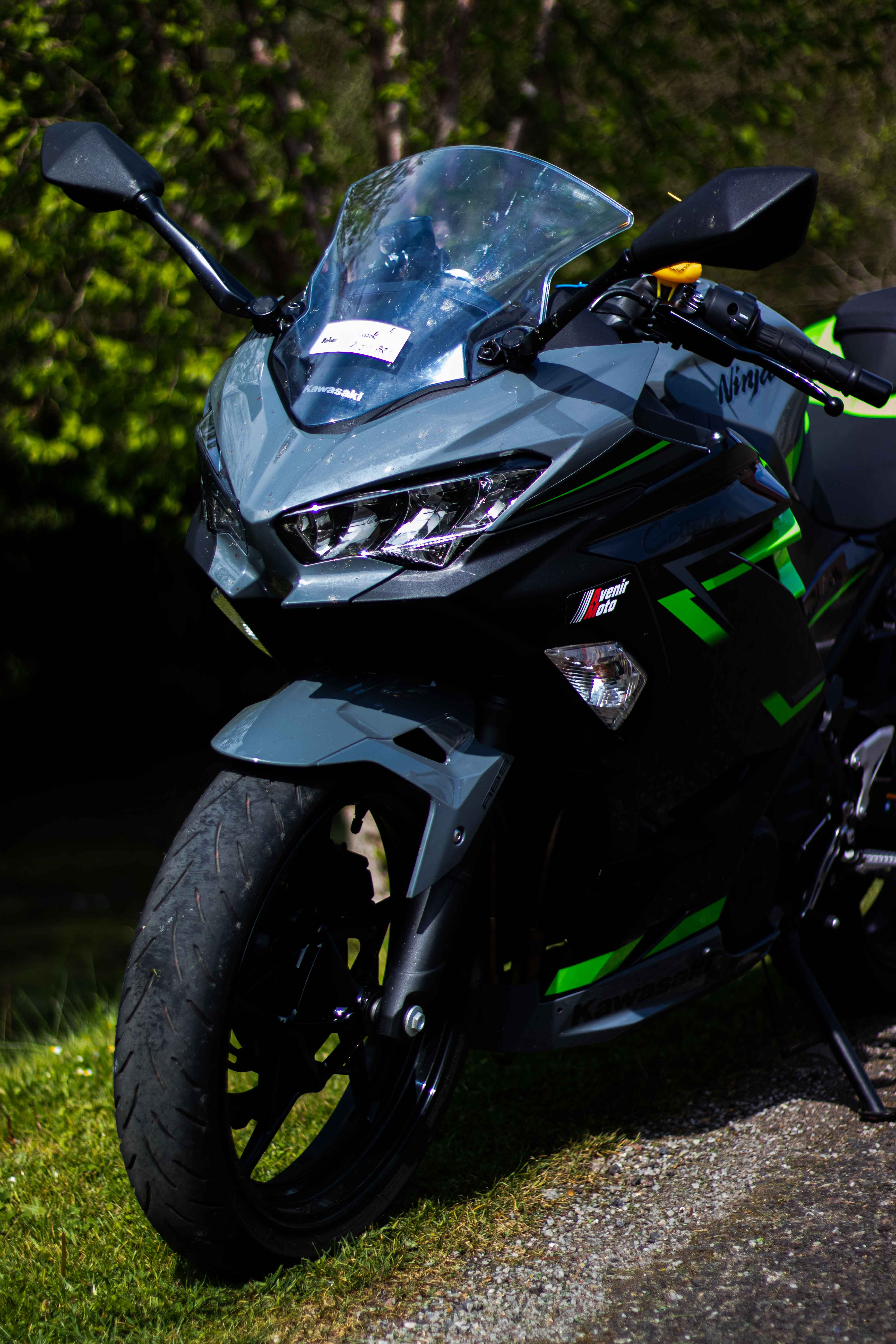 Photo d'une moto noir et verte, vu à trois quart face au format portrait